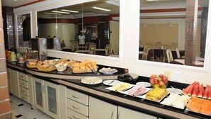 Ein Buffet mit verschiedenen Speisen und dahinter ein Essbereich, abgetrennt durch eine Glasscheibe.