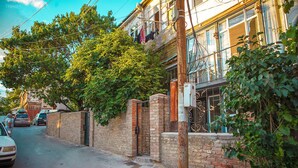 Una vista di una strada con un muro in mattoni, un palo di legno e un edificio con un balcone.