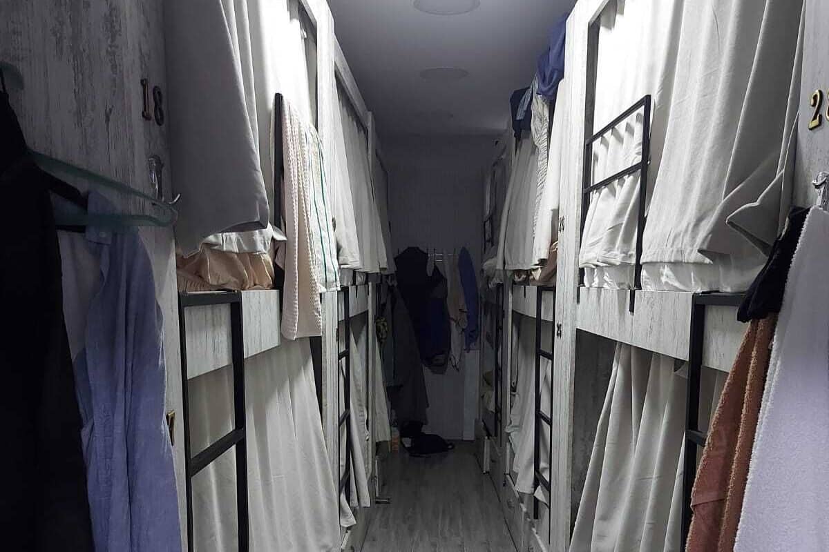 A corridor with bunk beds, each with a curtain and a number on the wall.