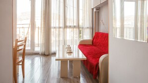 Una stanza con una sedia in legno, un tavolo bianco e un divano rosso.