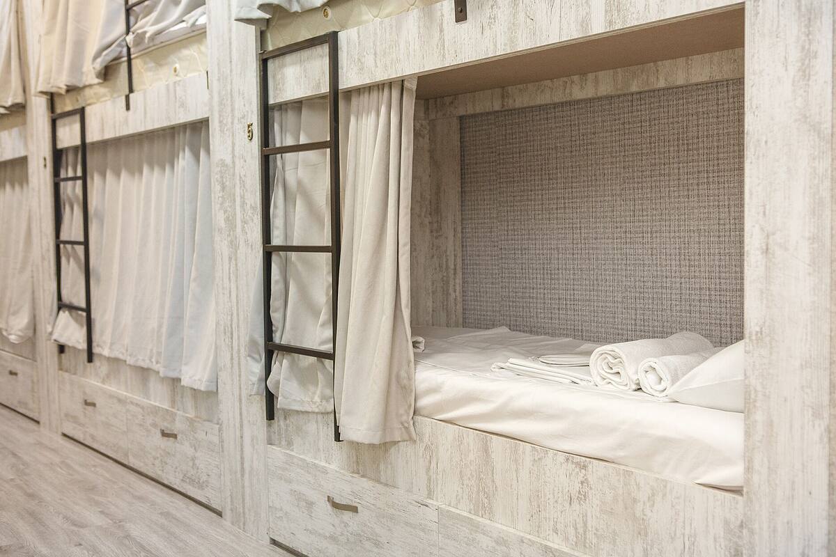 A bunk bed with a ladder, white curtains, and neatly folded towels.