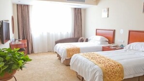 A hotel room with two beds, a desk, a chair, a potted plant, and a television. - Greentree Inn Jiangsu Changzhou Menghe Avenue Qiliang Jinfu Business Hotel (Changzhou)