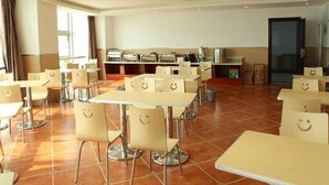 A spacious dining area with multiple tables and chairs, a kitchen area in the background, and a large window providing natural light. - Greentree Inn Jiangsu Changzhou Menghe Avenue Qiliang Jinfu Business Hotel (Changzhou)