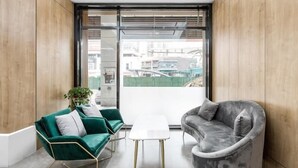 A modern interior with a green sofa set, a grey armchair, and a small white table.