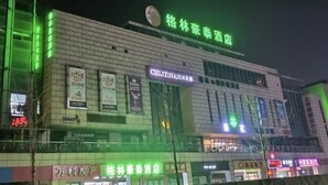 A hotel with a prominent sign in green letters, multiple banners advertising various services, and a modern architectural design.