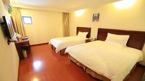 A hotel room with two beds, a desk, a chair, a TV, and a window with curtains.