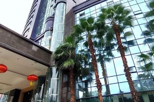 Un edificio moderno con fachada de vidrio y palmeras en primer plano.