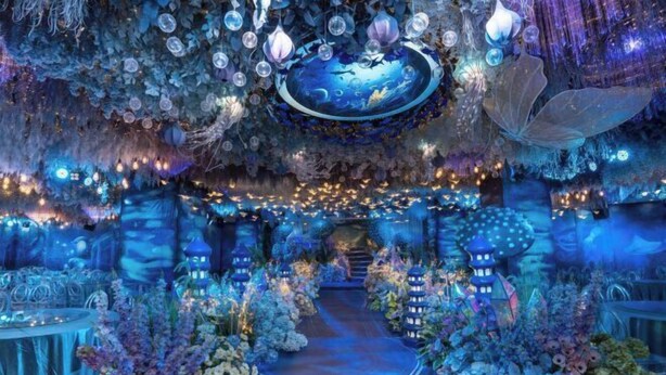 An indoor venue with a central pathway, decorative foliage, and hanging lanterns. - Wanxing Hotel (Qu County)