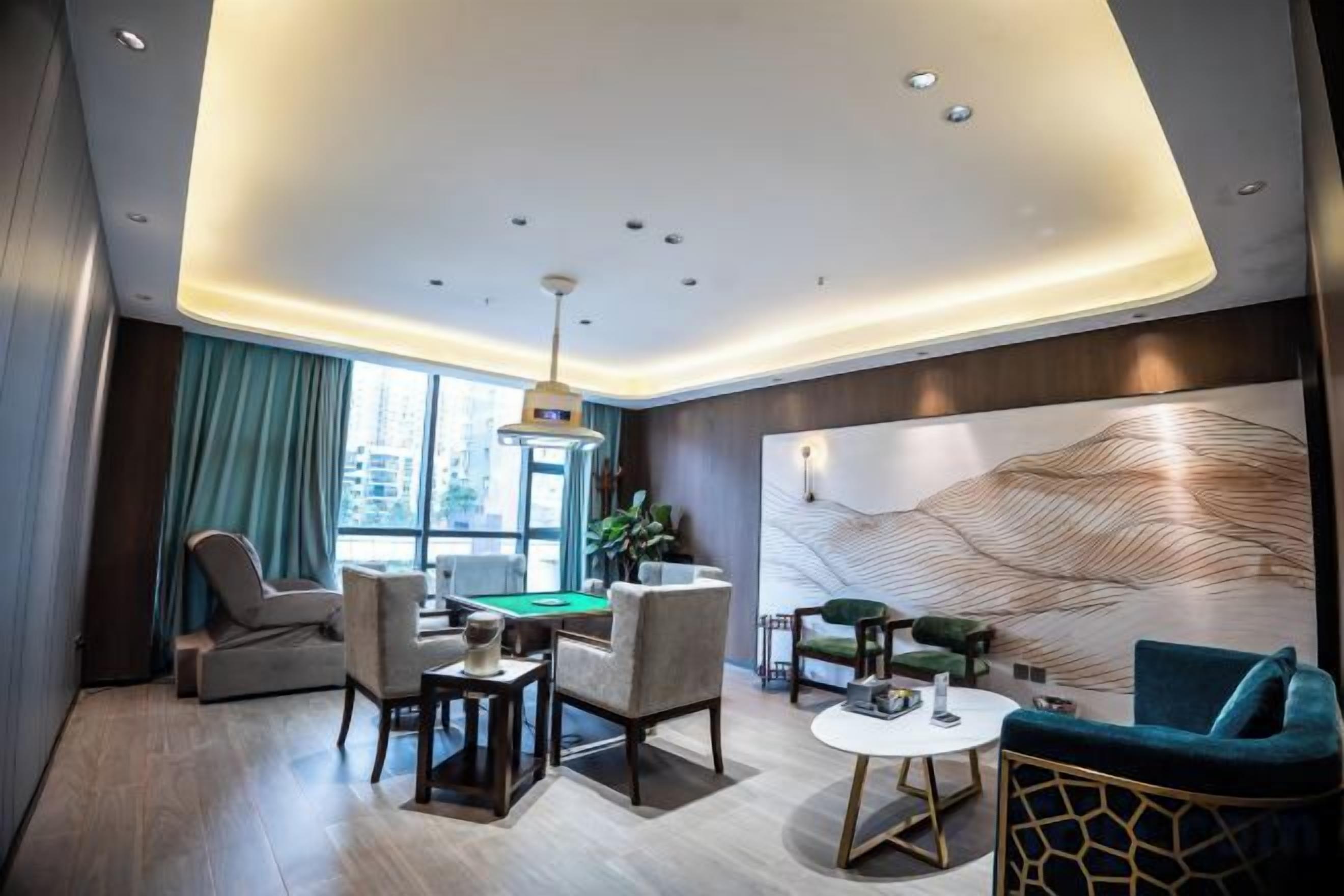A modern hotel room with a pool table, comfortable seating, a large window, and a decorative wall.