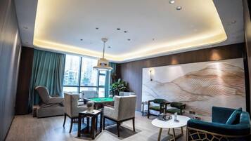 A modern hotel room with a pool table, comfortable seating, a large window, and a decorative wall.