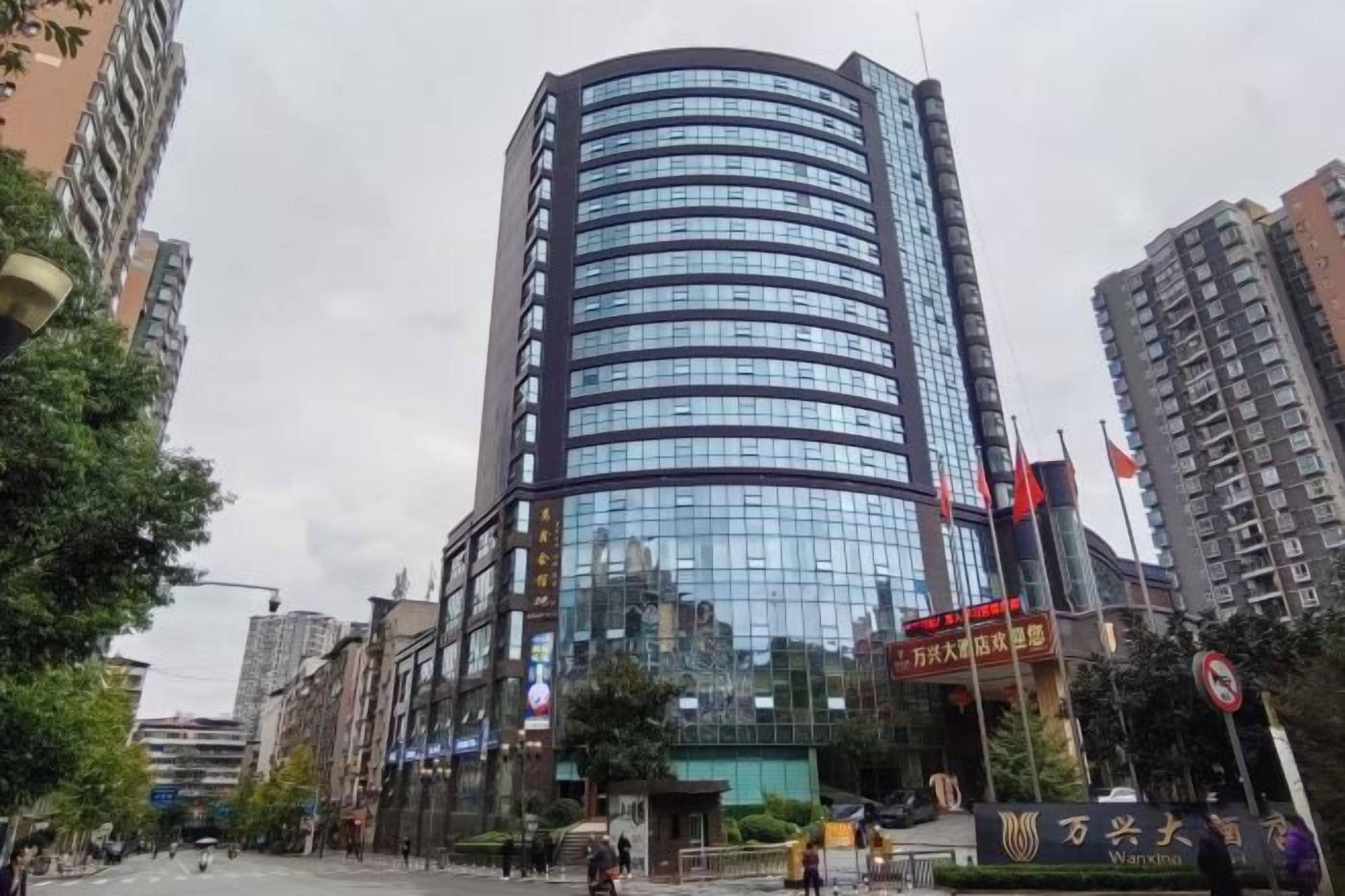 A modern high-rise building with a curved facade, surrounded by other buildings and trees.