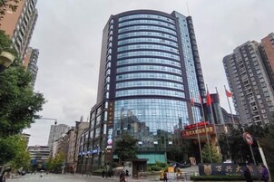 A modern high-rise building with a curved facade, surrounded by other buildings and trees.