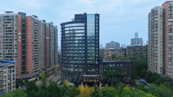 A high-rise building with a curved facade, surrounded by other residential buildings and greenery.