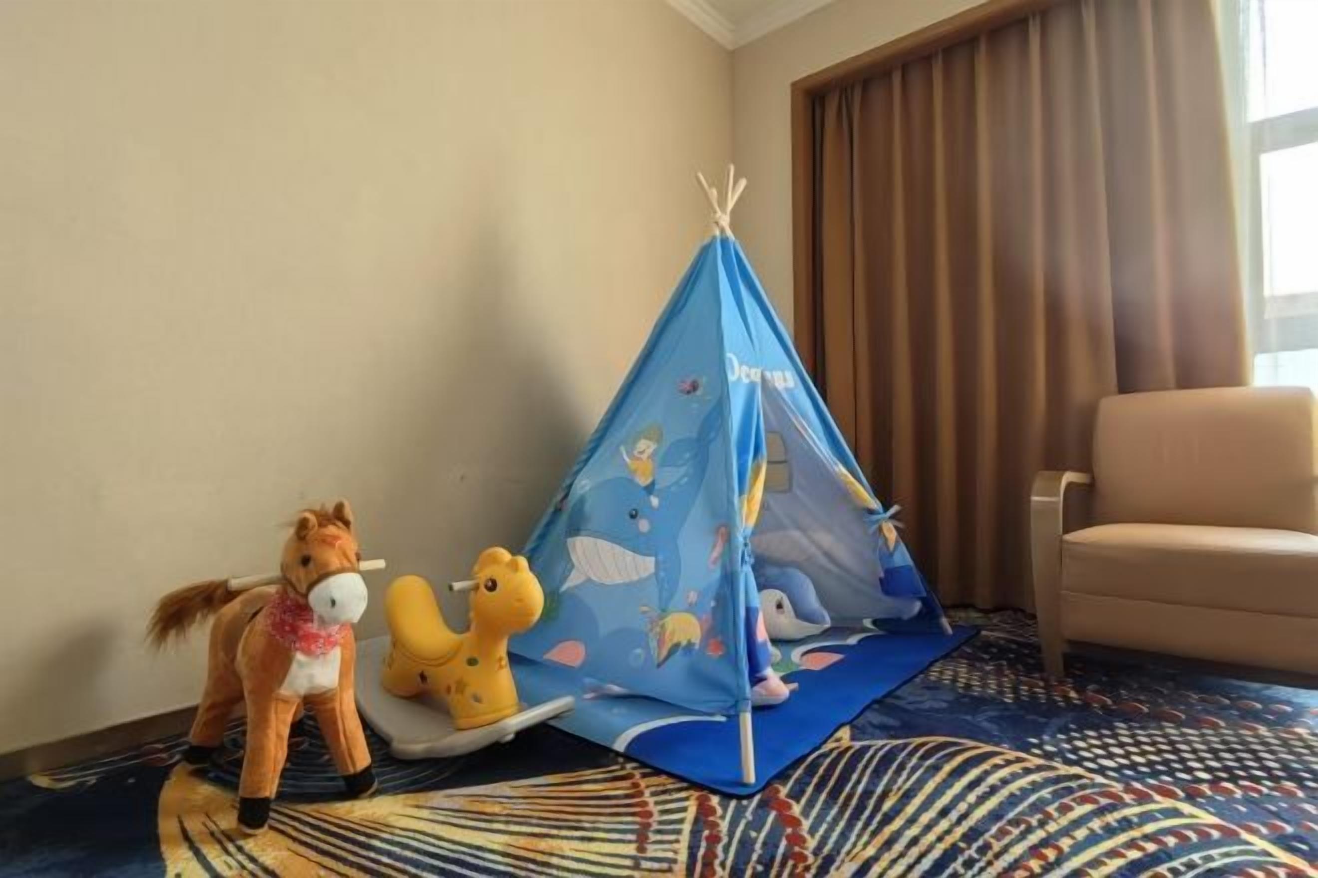 A room with a blue tent, a toy horse, and a toy dinosaur.