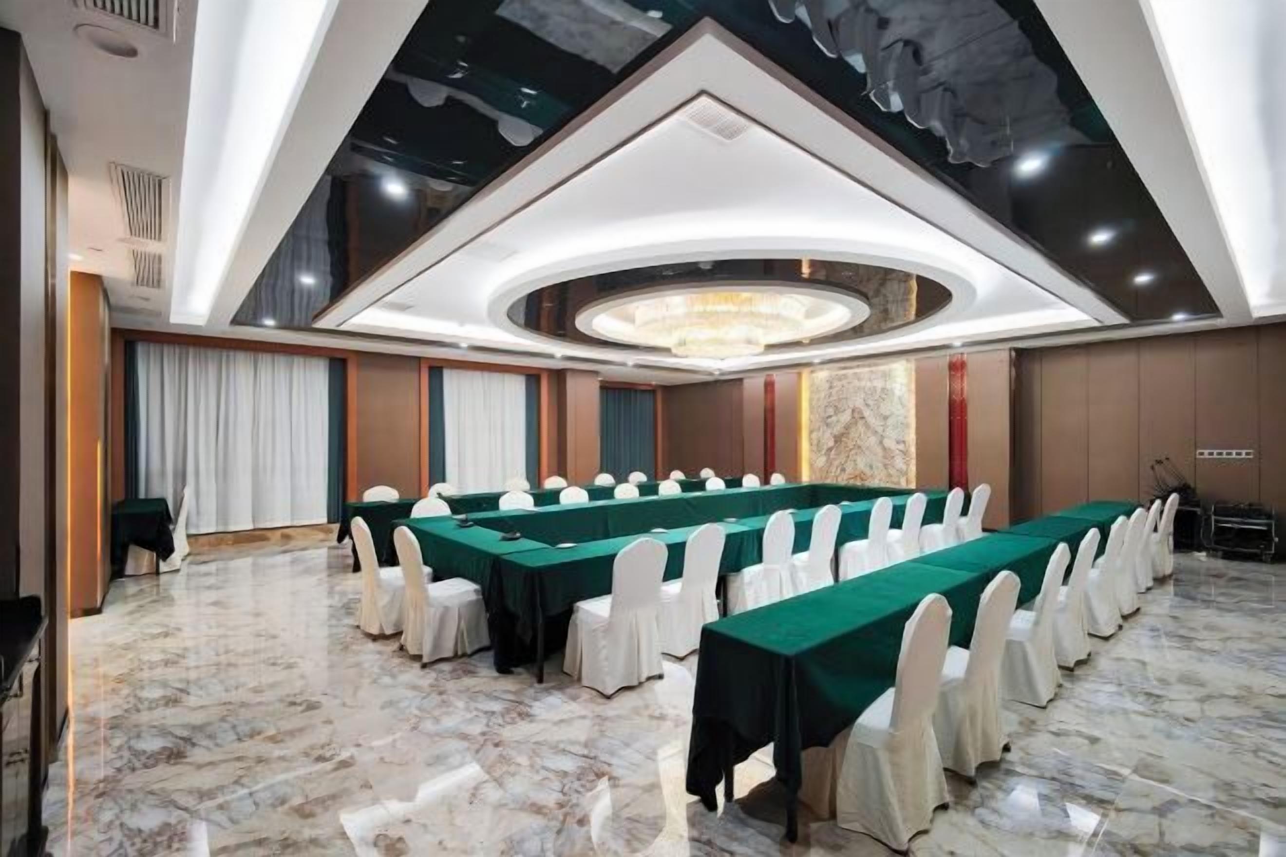 Uma sala de conferências com uma mesa comprida, cadeiras brancas e um lustre.