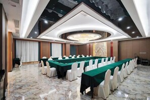 A conference room with a long table, white chairs, and a chandelier. - Wanxing Hotel (Qu County)