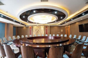 Une salle de conférence équipée d’une table ronde, de chaises et d’un lustre.
