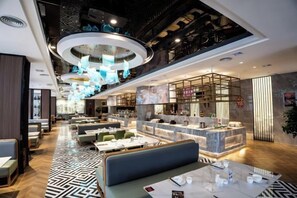 A modern restaurant with a high ceiling, circular lighting fixtures, and a bar area. - Wanxing Hotel (Qu County)