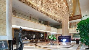 A spacious lobby with a high ceiling, a central fountain, and a seating area. - Wanxing Hotel (Qu County)