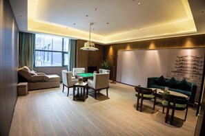 A modern living room with a sofa, a coffee table, and a dining table with chairs. - Wanxing Hotel (Qu County)