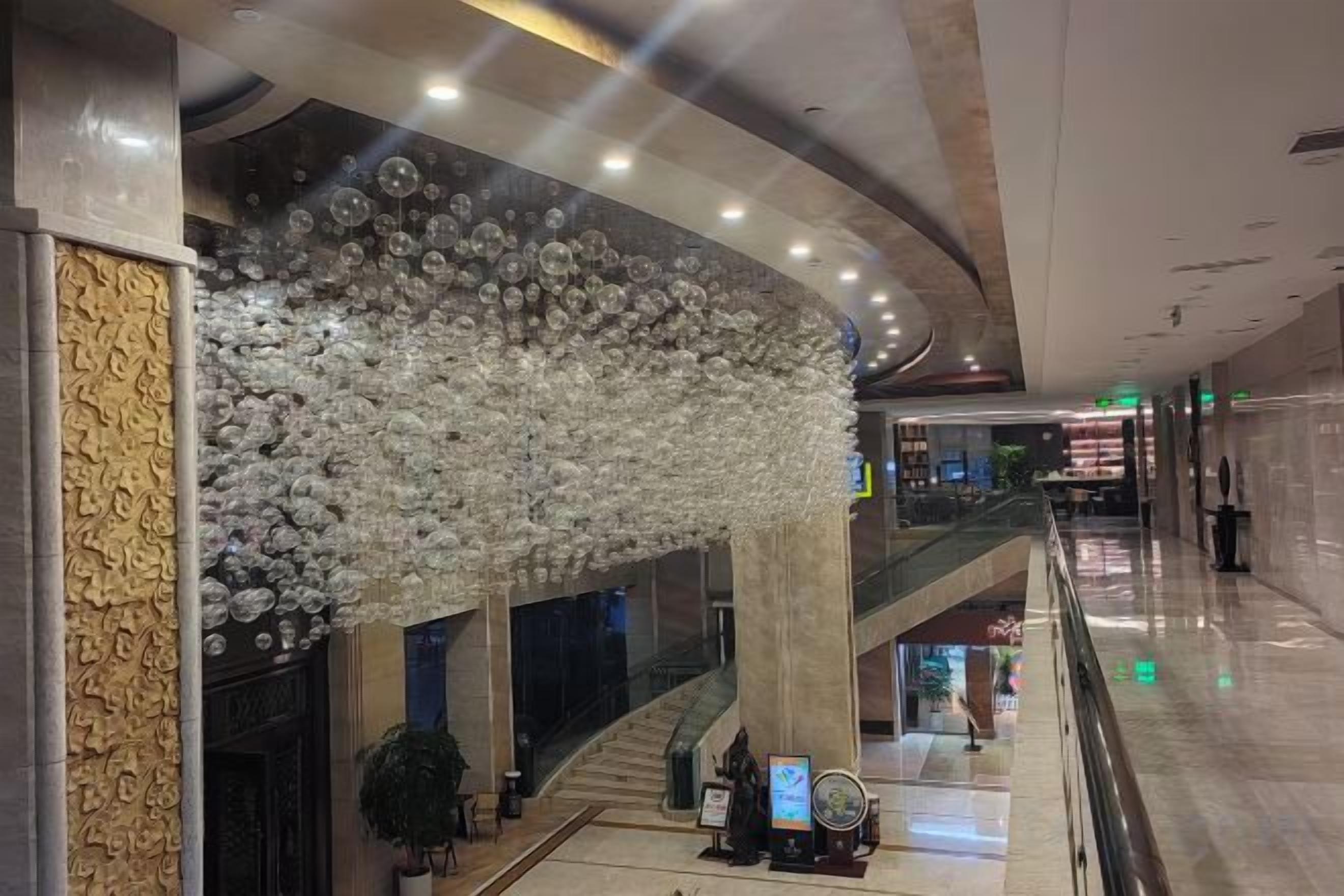 A spacious indoor area with a curved ceiling, a staircase, and a decorative light installation.