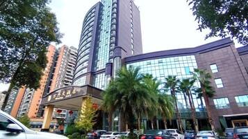Hotel com fachada moderna, estacionamento e palmeiras.