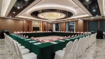 A conference room with a long table, white chairs, and a chandelier.