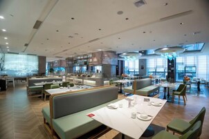 Un restaurante moderno con varias zonas de comedor, incluidas mesas y cabinas, y una zona de bar.
