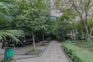 A pathway lined with trees and benches in a park-like setting.