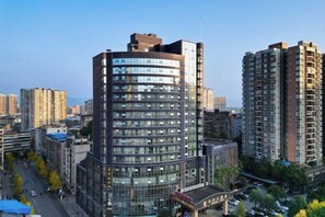 A high-rise building with multiple floors, surrounded by other high-rise buildings in an urban setting. - Wanxing Hotel (Qu County)