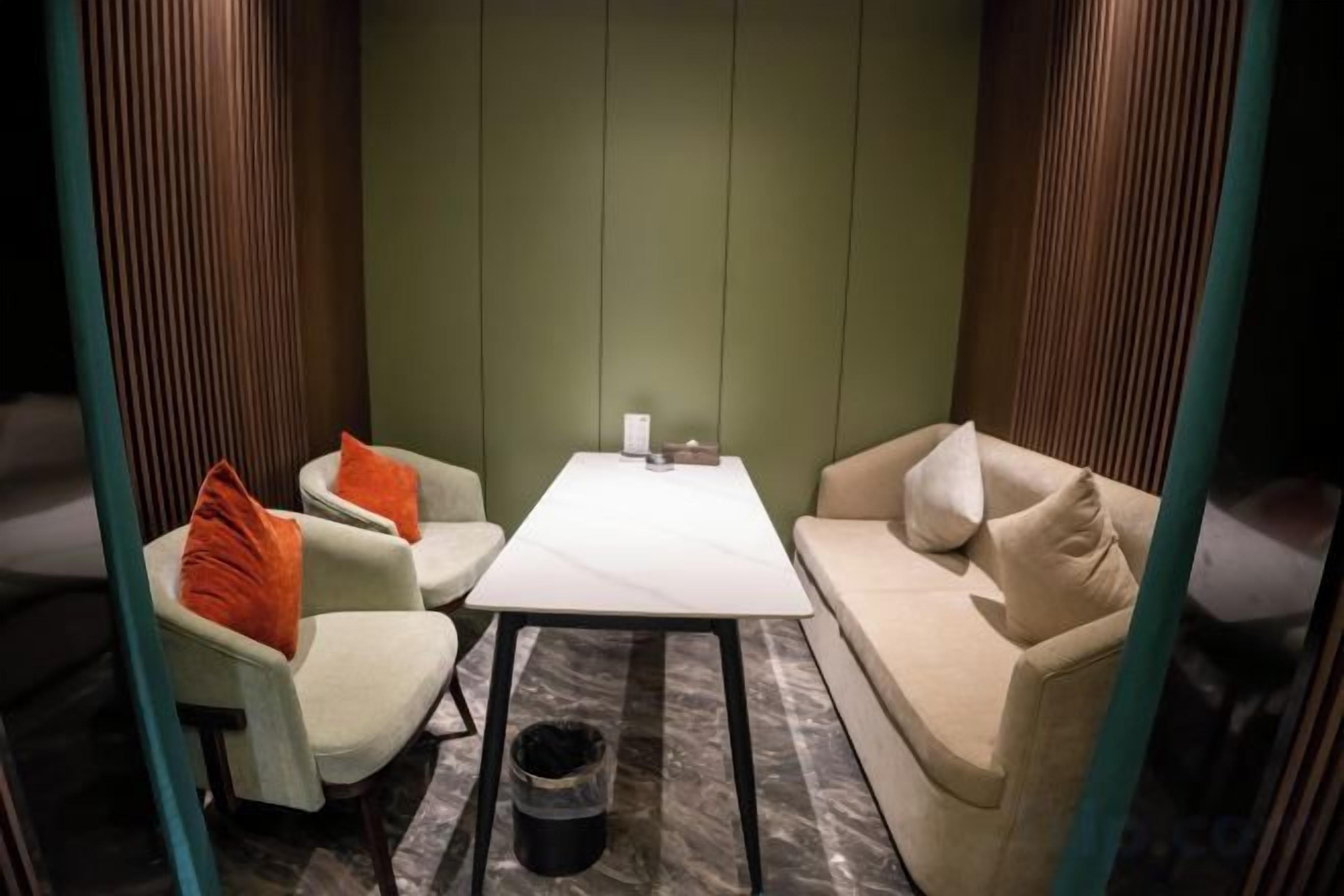 Ein Zimmer mit einer Couch, zwei Sesseln, einem kleinen Tisch und einem Mülleimer.