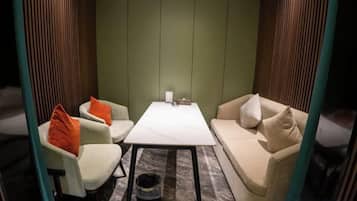 Ein Zimmer mit einer Couch, zwei Sesseln, einem kleinen Tisch und einem Mülleimer.