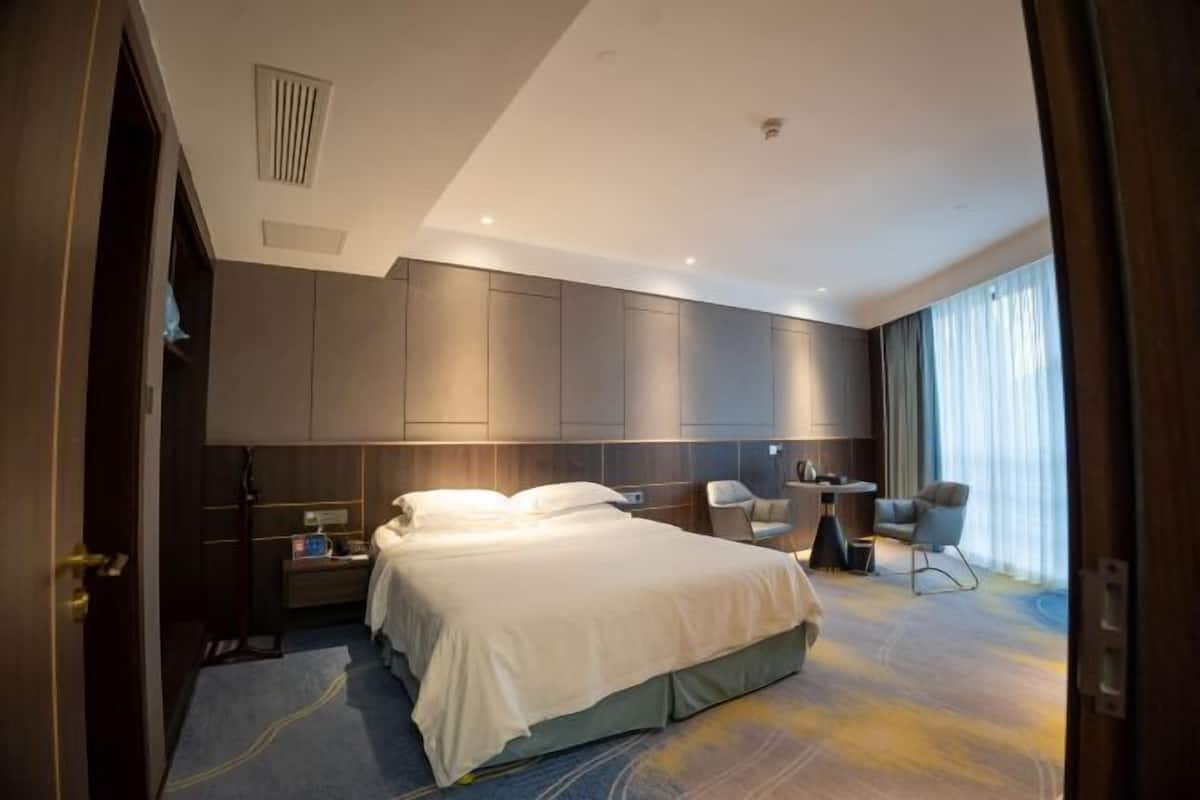 A modern hotel room with a large bed, a desk, and a chair.