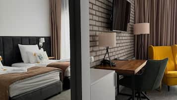 Ein Hotelzimmer mit Backsteinwand, einem Flachbildfernseher, einem Schreibtisch mit Stuhl, einem Bett mit Kopfteil und einem gelben Sessel.
