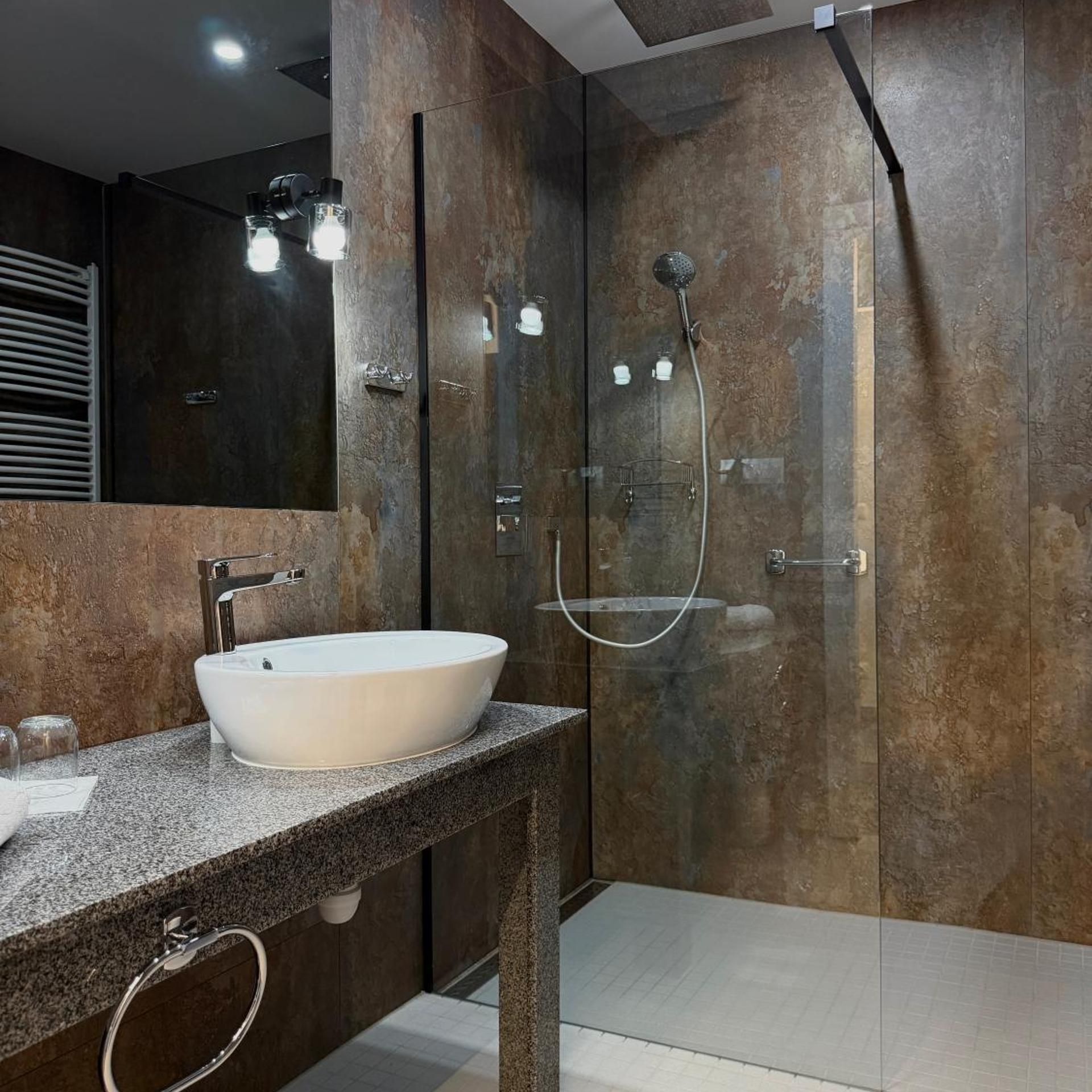 Ein modernes Badezimmer mit einem großen Waschbecken, einer Duschkabine und einem Spiegel über dem Waschbecken.