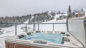 Un bain à remous avec une structure extérieure en bois, installé devant un paysage montagneux enneigé.