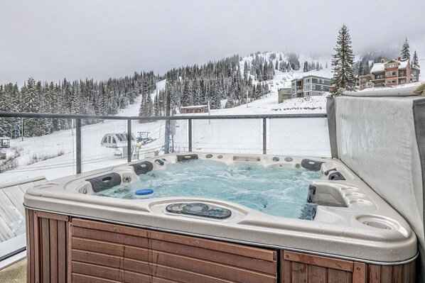 Un bain à remous avec une structure extérieure en bois, installé devant un paysage montagneux enneigé.