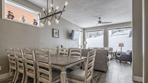 Un coin repas avec une table et des chaises en bois, un lustre et un téléviseur fixé au mur.