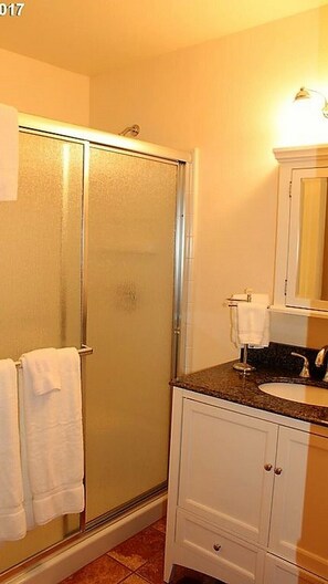 A bathroom with a glass shower door, a sink with a mirror, and a towel rack. - A River Cottage for Every Season (Mapleton)