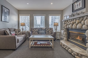 A cozy living room with a fireplace, a sofa, a coffee table, and a fireplace mantle.