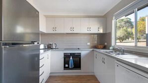 Una cocina moderna con armarios blancos, electrodomésticos de acero inoxidable y piso de madera.