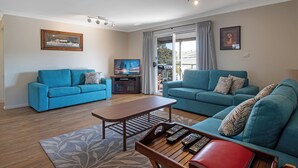 Un salón con dos sofás azules, una mesa de centro de madera y un televisor.
