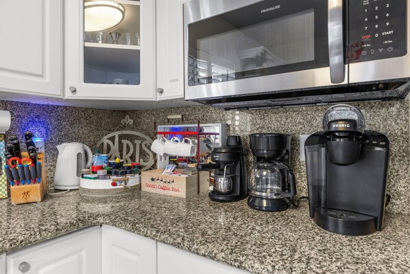 Une cuisine équipée d’un four à micro-ondes, d’une machine à café et d’un espace dédié au café, avec une boîte de café de la marque « Santa’s Coffee Bar ».
