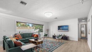 Een moderne woonkamer met een groene bank, een bijzettafeltje en een groot raam.