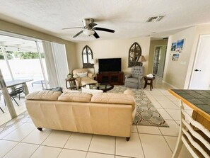 A living room with a sofa, a television, and a ceiling fan.