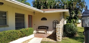 A building with a stone wall, a bench, and a sign.