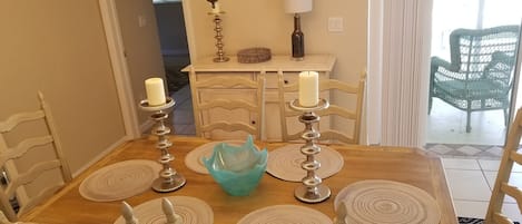 A dining table with four chairs, two candles, and a decorative bowl.