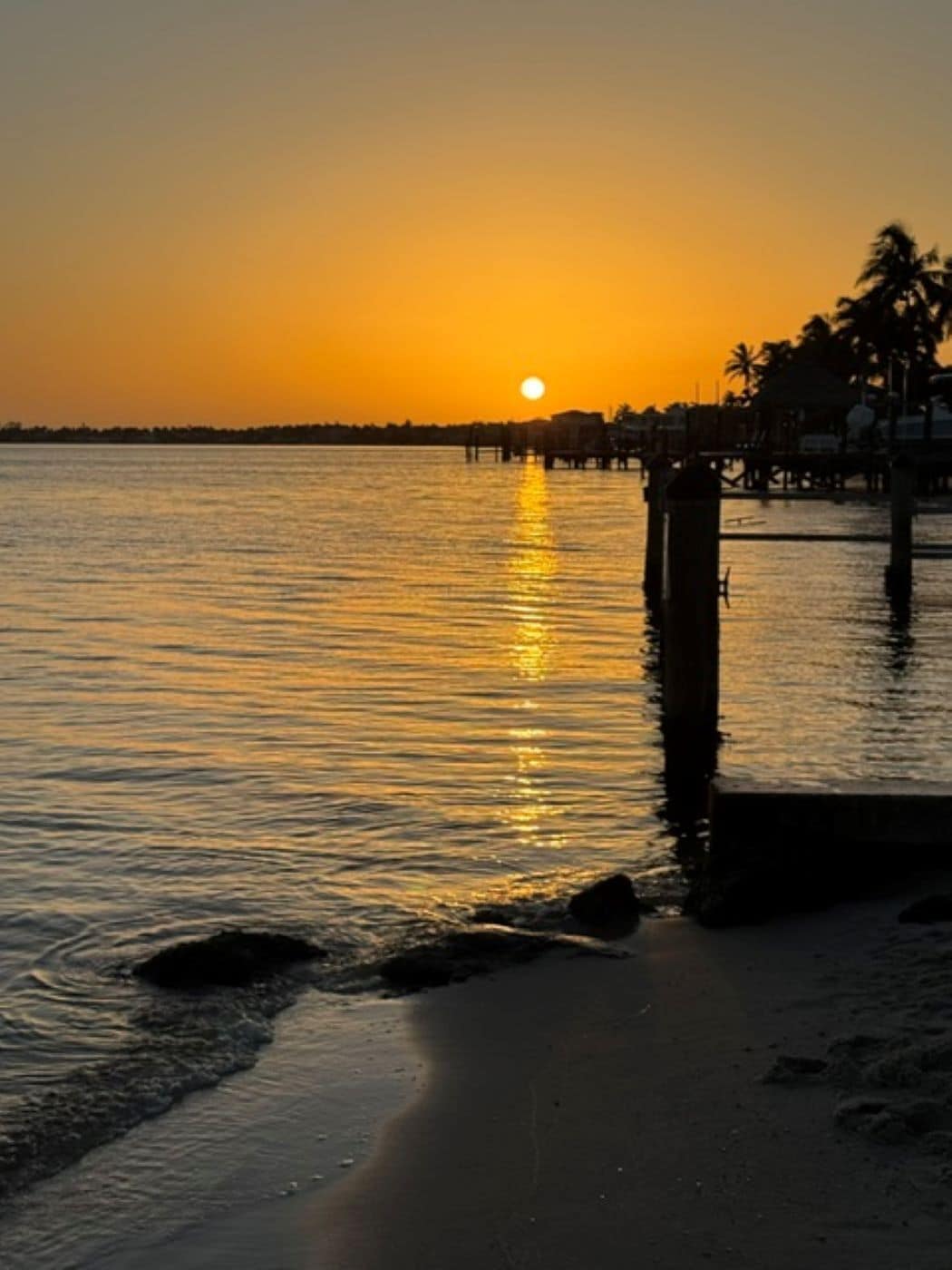 A sunset over a calm body of water with a pier extending into the water.