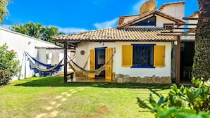 Une maison avec un toit en tuiles, un hamac et un mur en pierre.