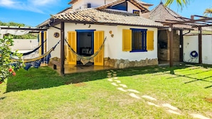 Une maison avec un toit recouvert de tuiles, une antenne parabolique et un hamac dans la cour.